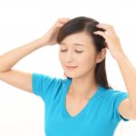 低気圧頭痛の予防にヘッドマッサージをする女性